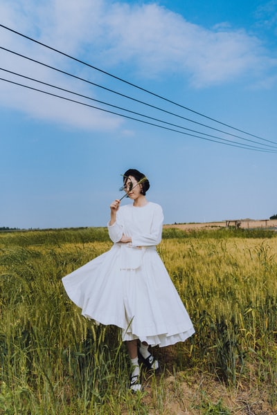 白衣女子白天站在蓝天下绿草如茵的草地上